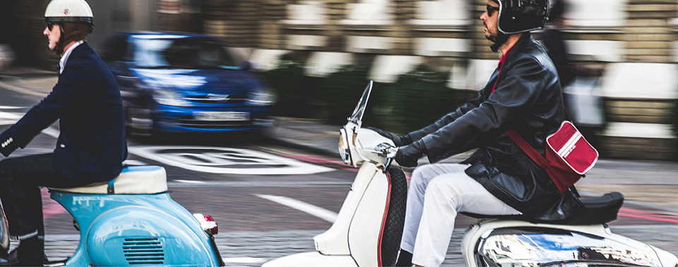 Two men riding scooters in traffic